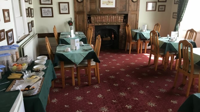 The breakfast room, with tables laid by the fireplace