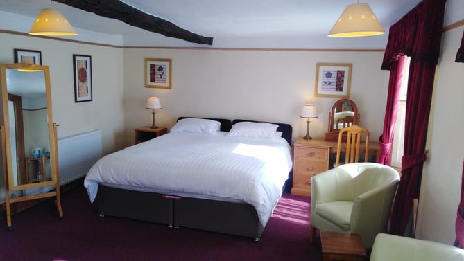 Room 4: a superking bed under the old beams, with armchairs by the window